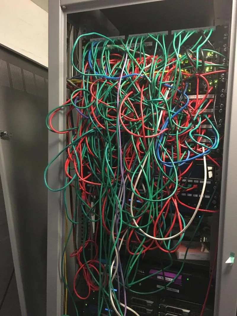 A tangled comms rack before remediation